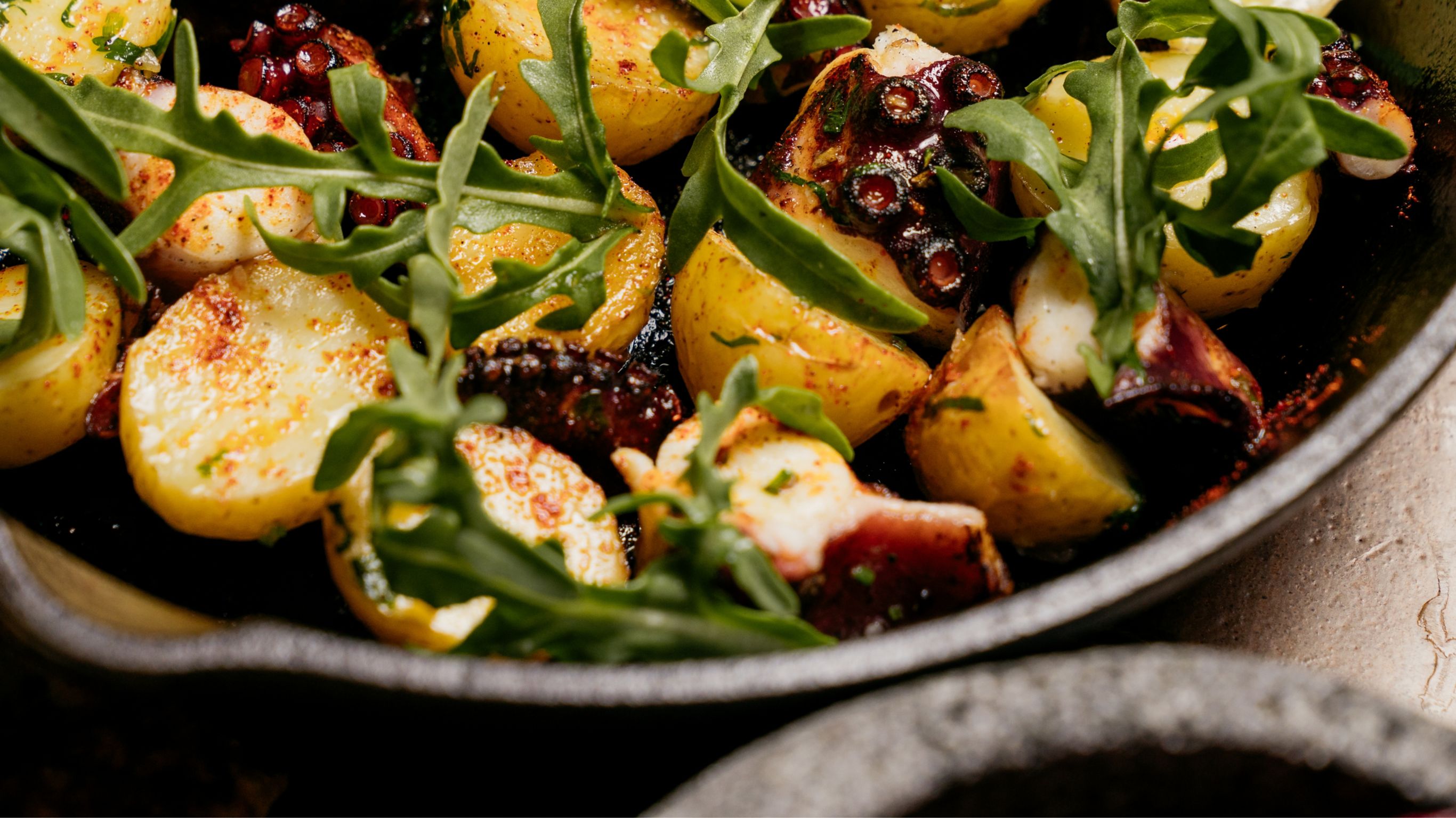 Zapote dish of potatoes, octopus and herbs in a cast iron skillet